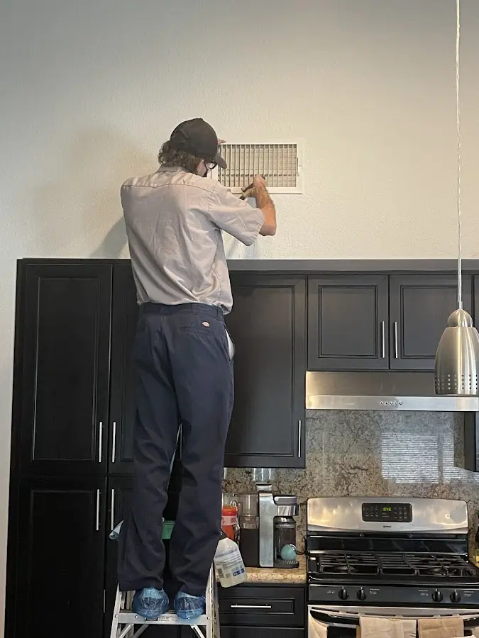 Technician inspecting an air vent during HVAC service in Sudley
